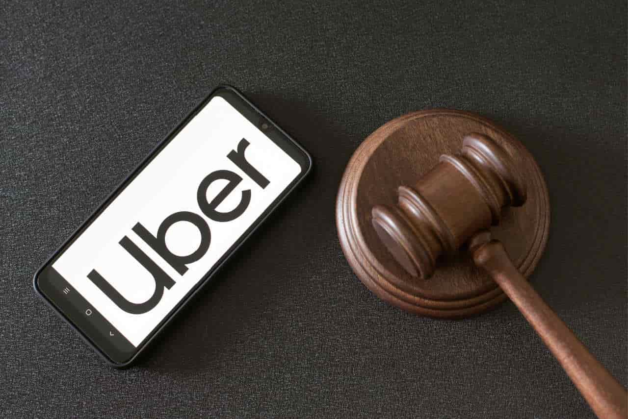 smartphone exibe logo da Uber próximo de martelo da justiça