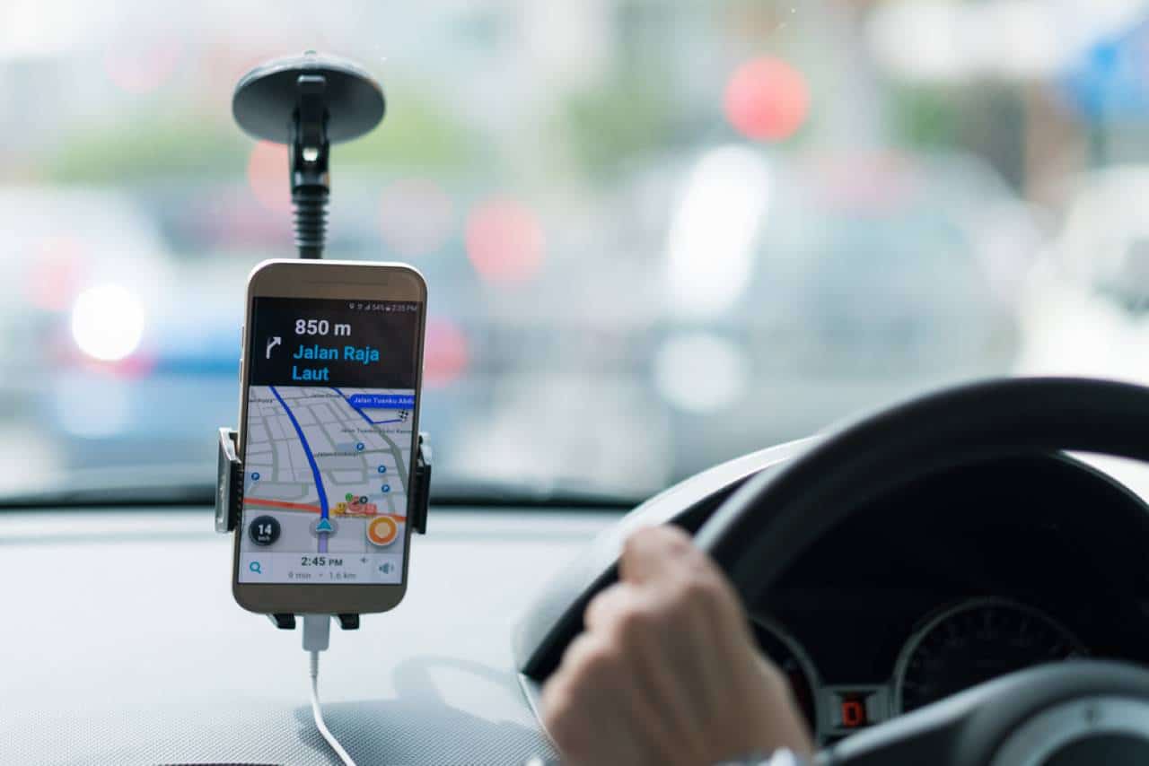 Celular no vidro do carro exibindo app de transporte