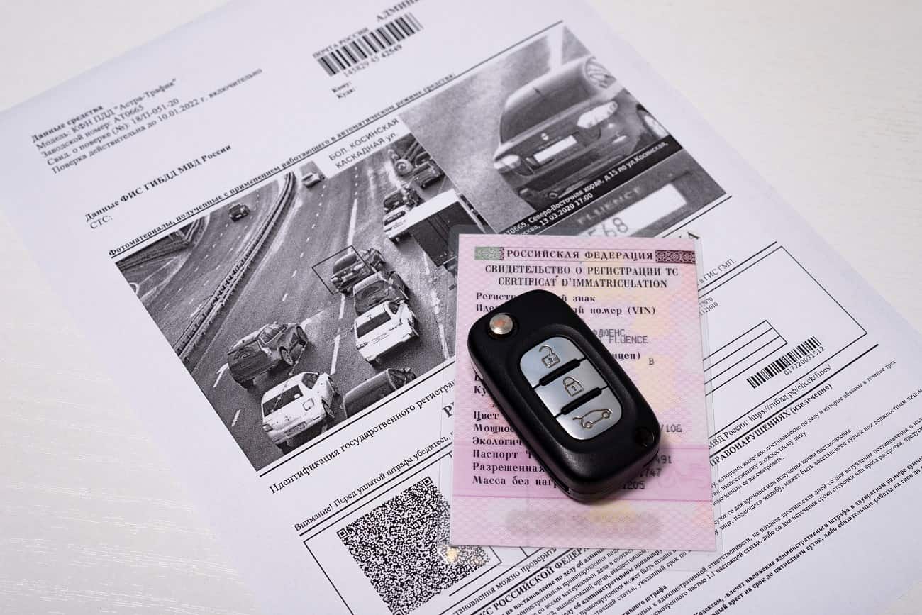 chave de carro em cima de uma autuação de trânsito sobre uma mesa branca e lisa