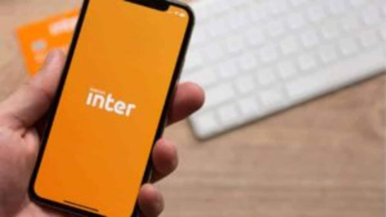 Pessoa segurando celular que exibe logo do banco Inter