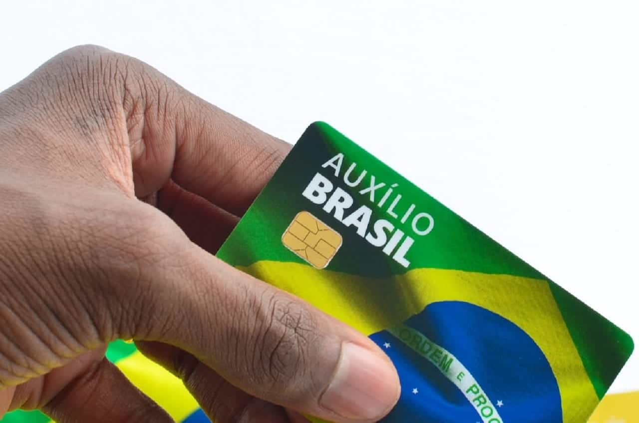 Imagem de uma pessoa segurando um cartão do Auxílio Brasil.