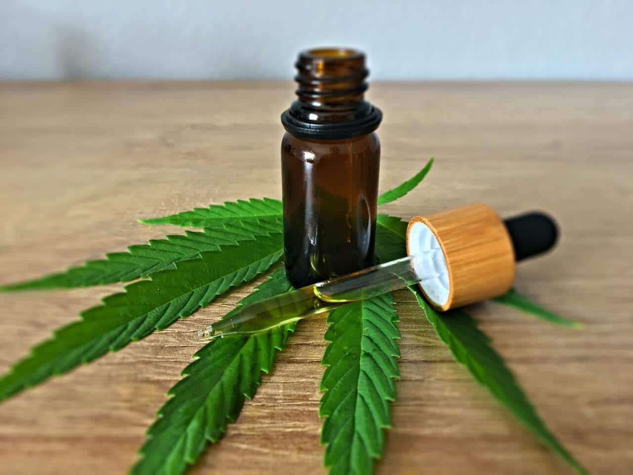 Folha de cannabis com frasco em cima com canabidiol