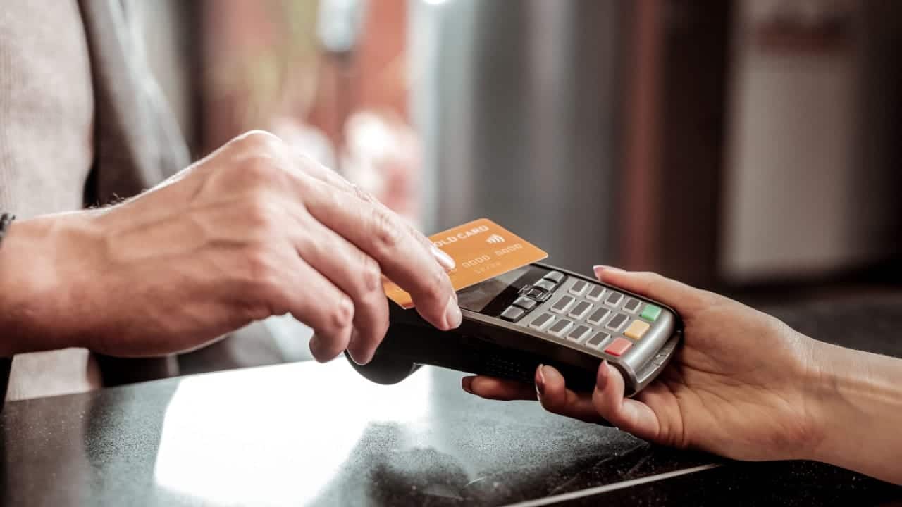 Mão aproximando cartão de máquina de cartões