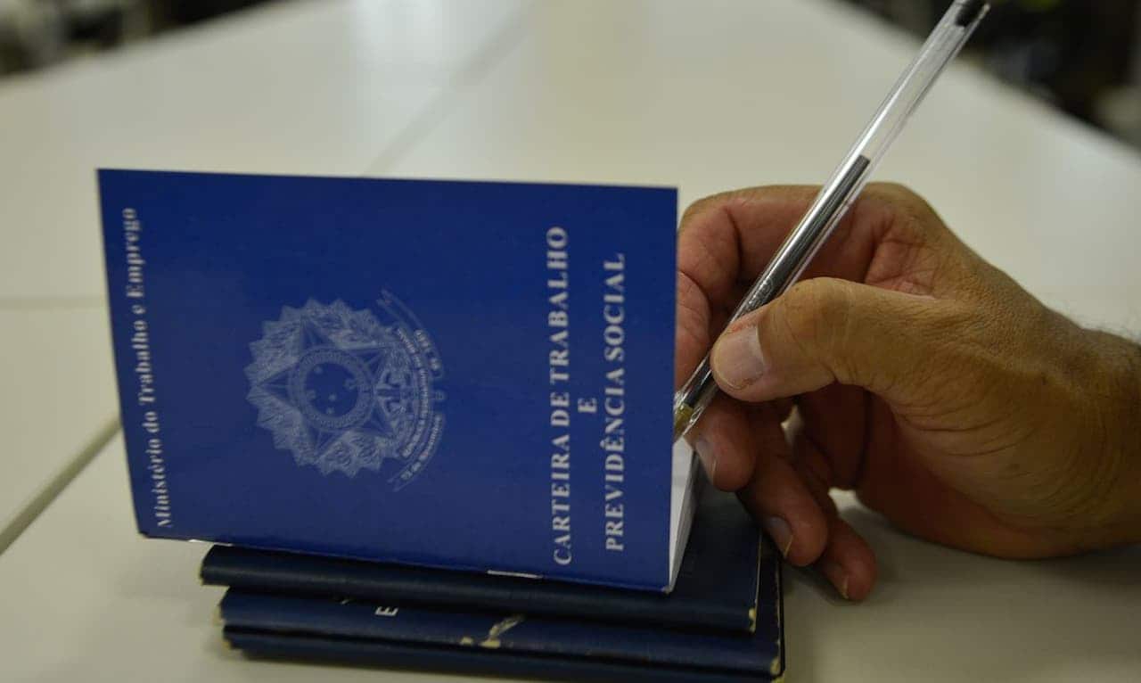 mão assinando carteira de trabalho