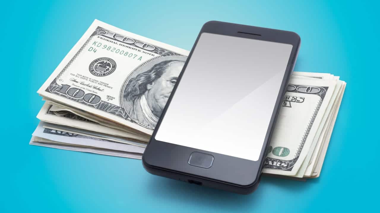 Celular sobre um monte de notas de dólar