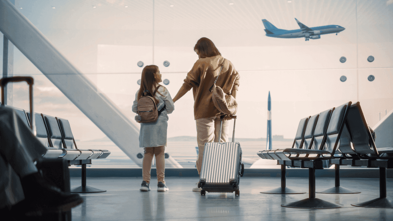 Imagem de mãe e filha de costas com malas em aeroporto