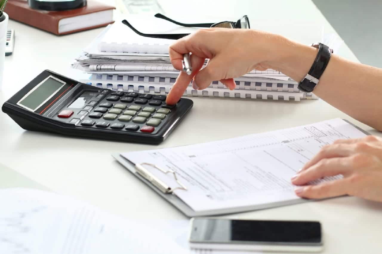 Pessoa utilizando uma calculadora enquanto analisa um documento.