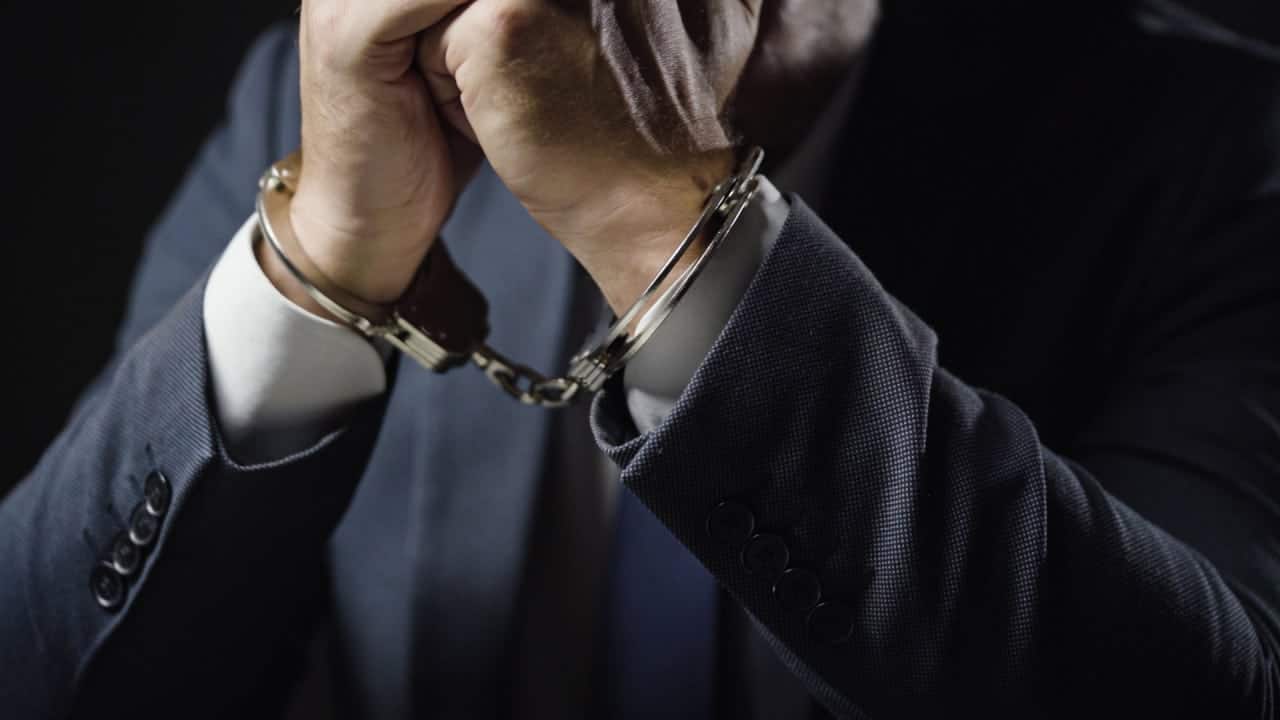 Mãos de um homem algemado e vestido de terno