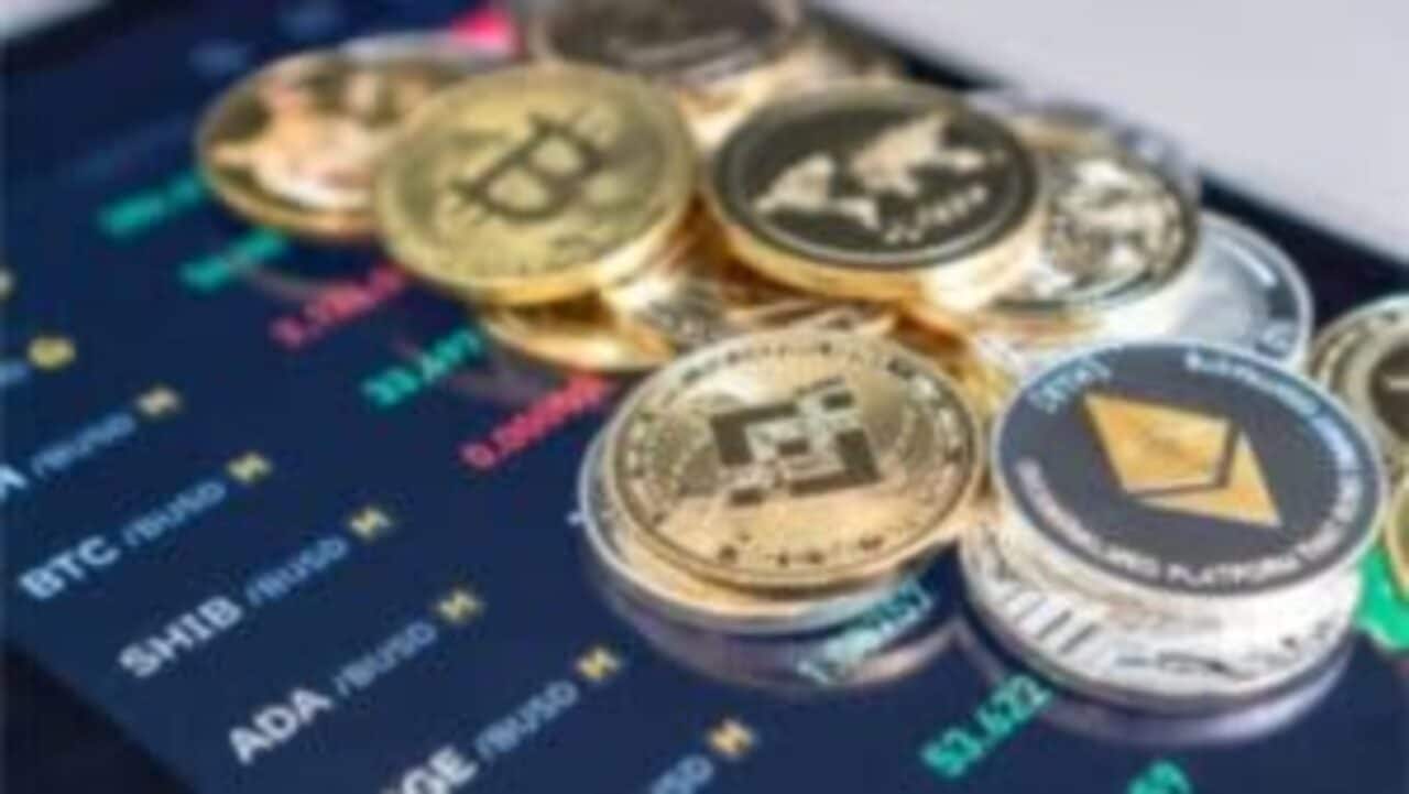 Diversos tipos de criptomoedas em cima de uma tela azul com cotações
