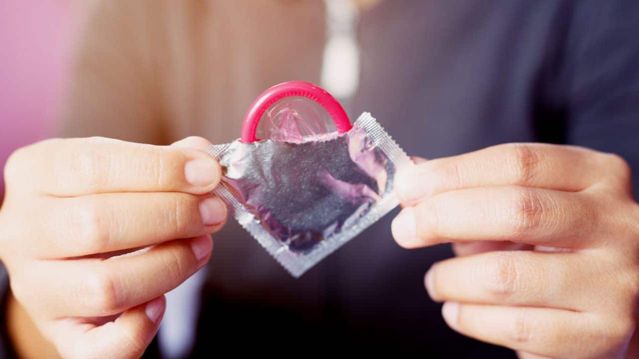 homem segurando um preservativo masculino aberto
