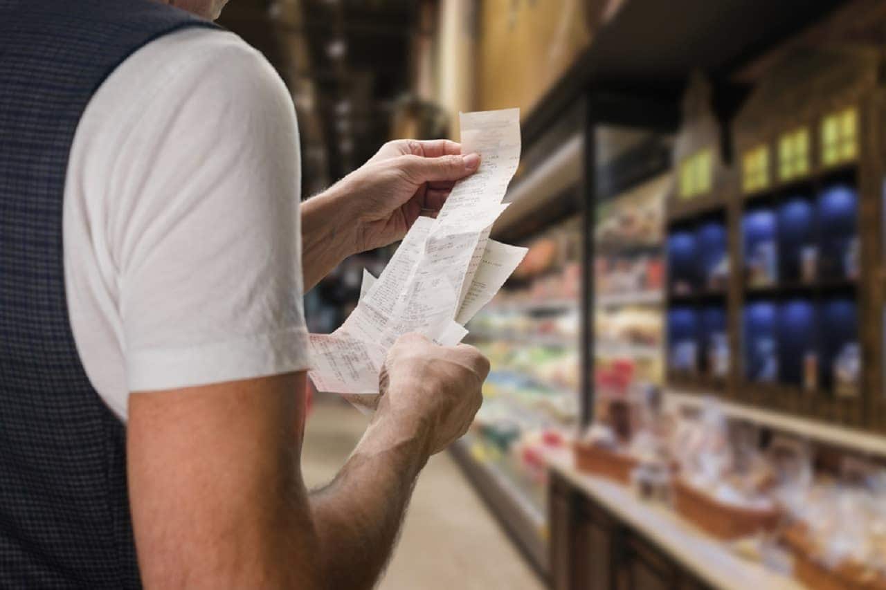 Pessoa segurando notas fiscais enquanto está em um mercado.