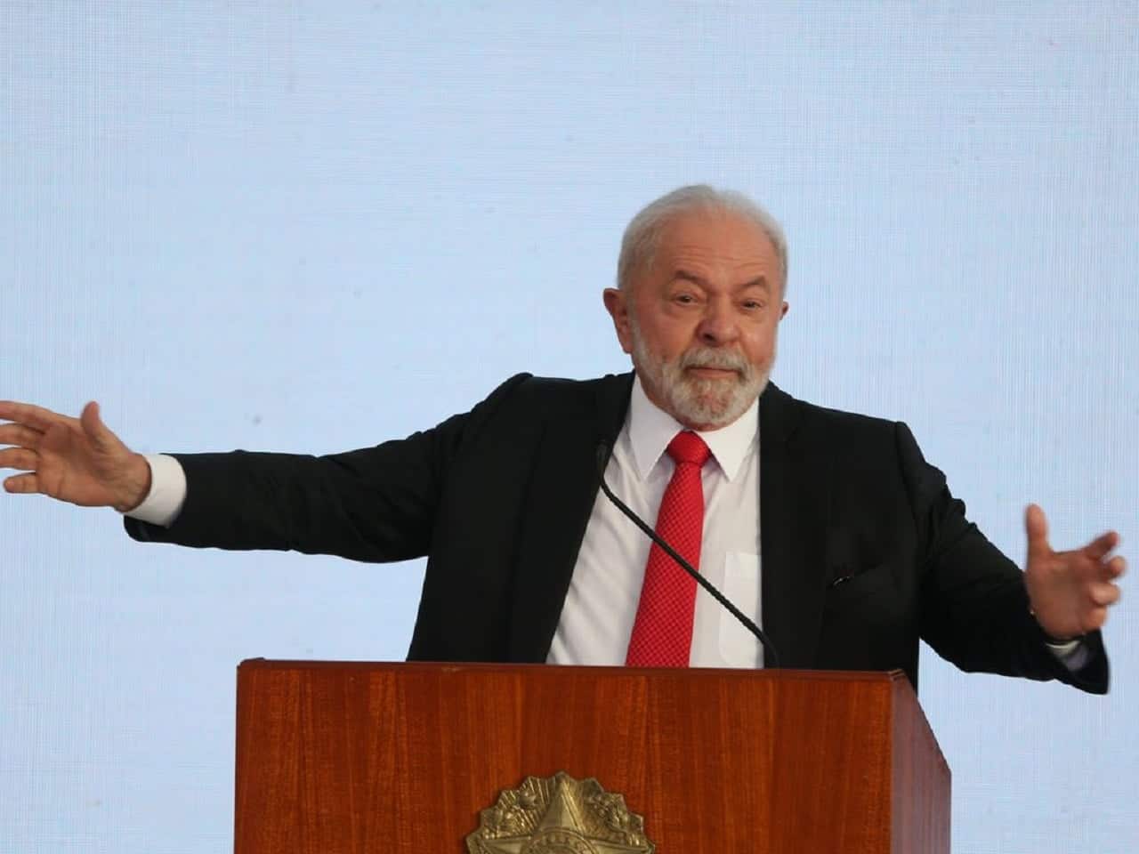 Imagem de Lula discursando e com os braços abertos.