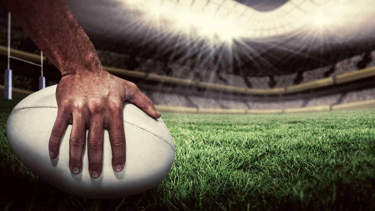 mão segurando bola de rúgbi