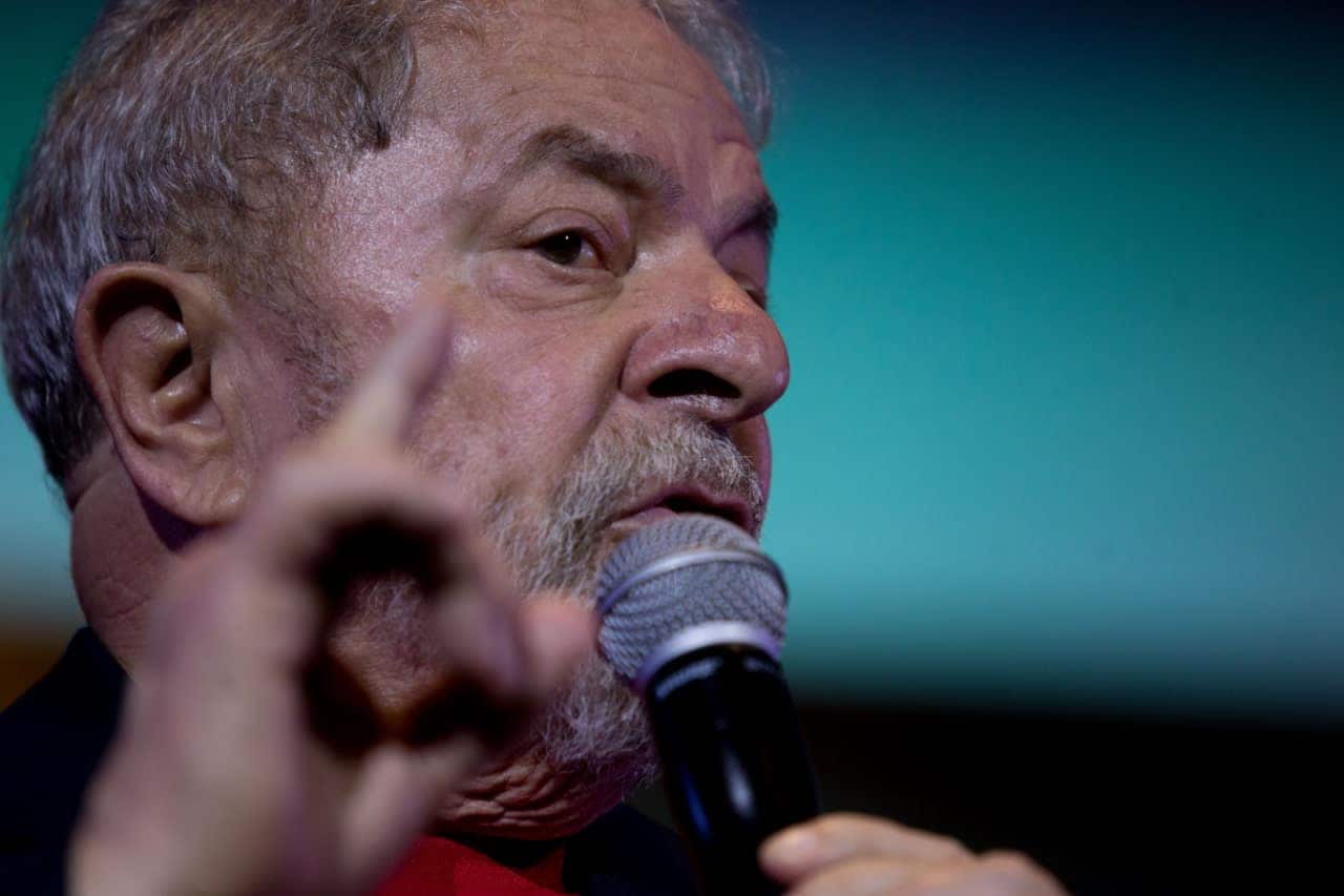 Imagem do presidente Lula, em discurso, com microfone em uma das mãos e o dedo indicador levantado próximo ao rosto