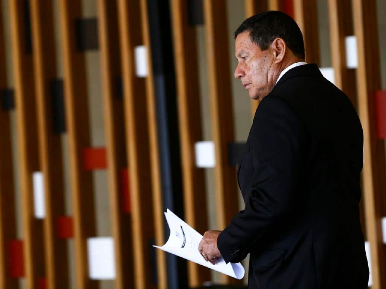 Imagem de perfil do ex-vice-presidente Mourão segurando documentos.