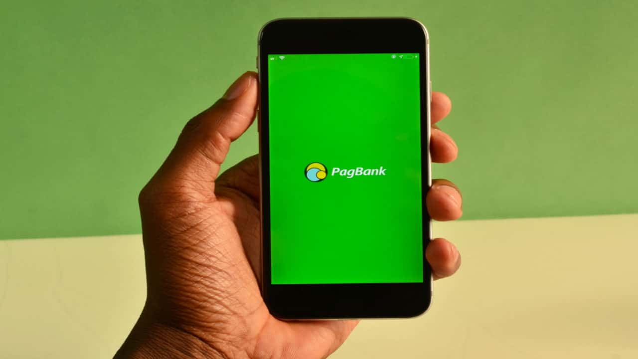 Pessoa segurando um celular que exibe a tela inicial do aplicativo do PagBank