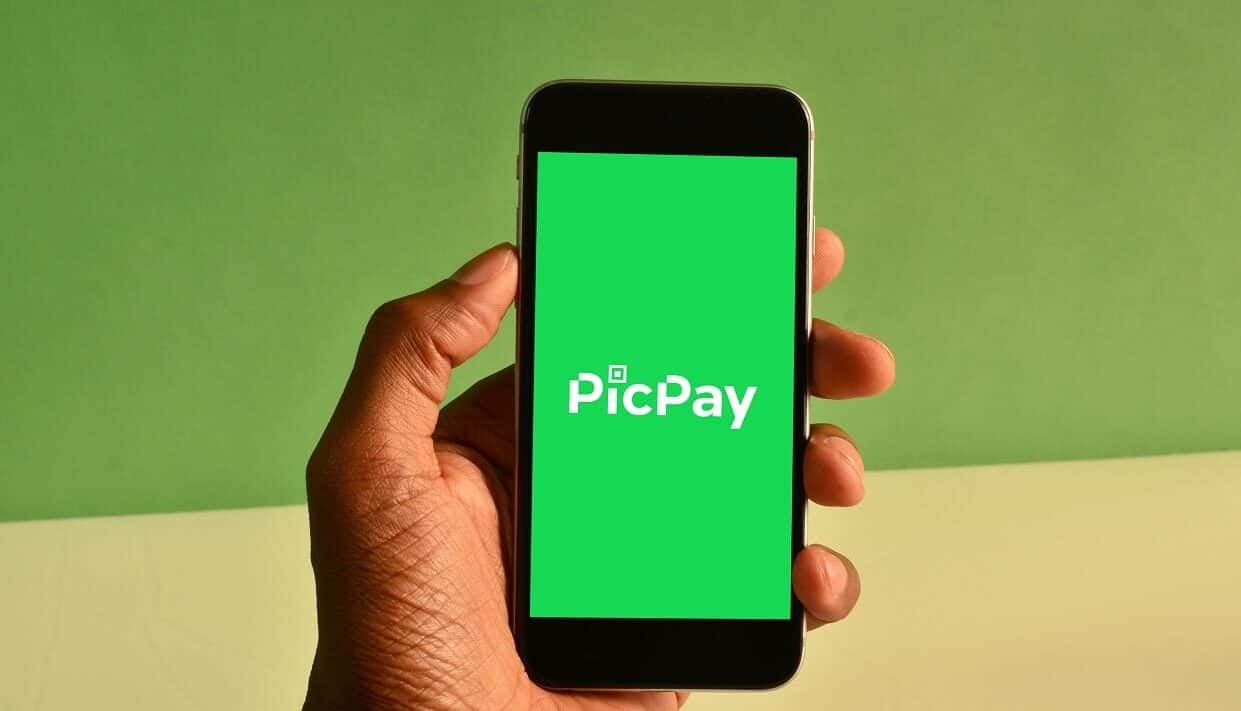 Mão segurando um smartphone com a logo do PicPay na tela