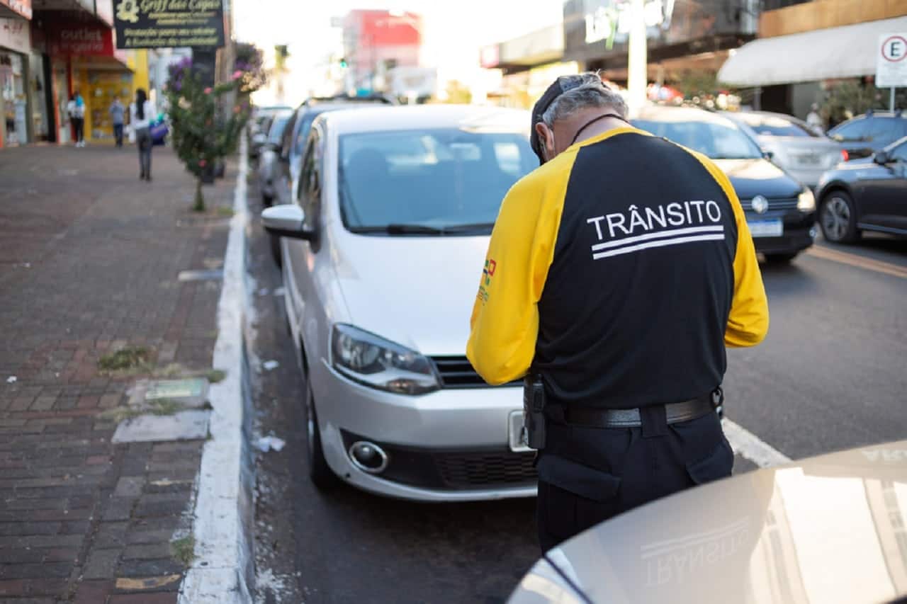 Imagem de uma pessoa anotando/multando um carro.