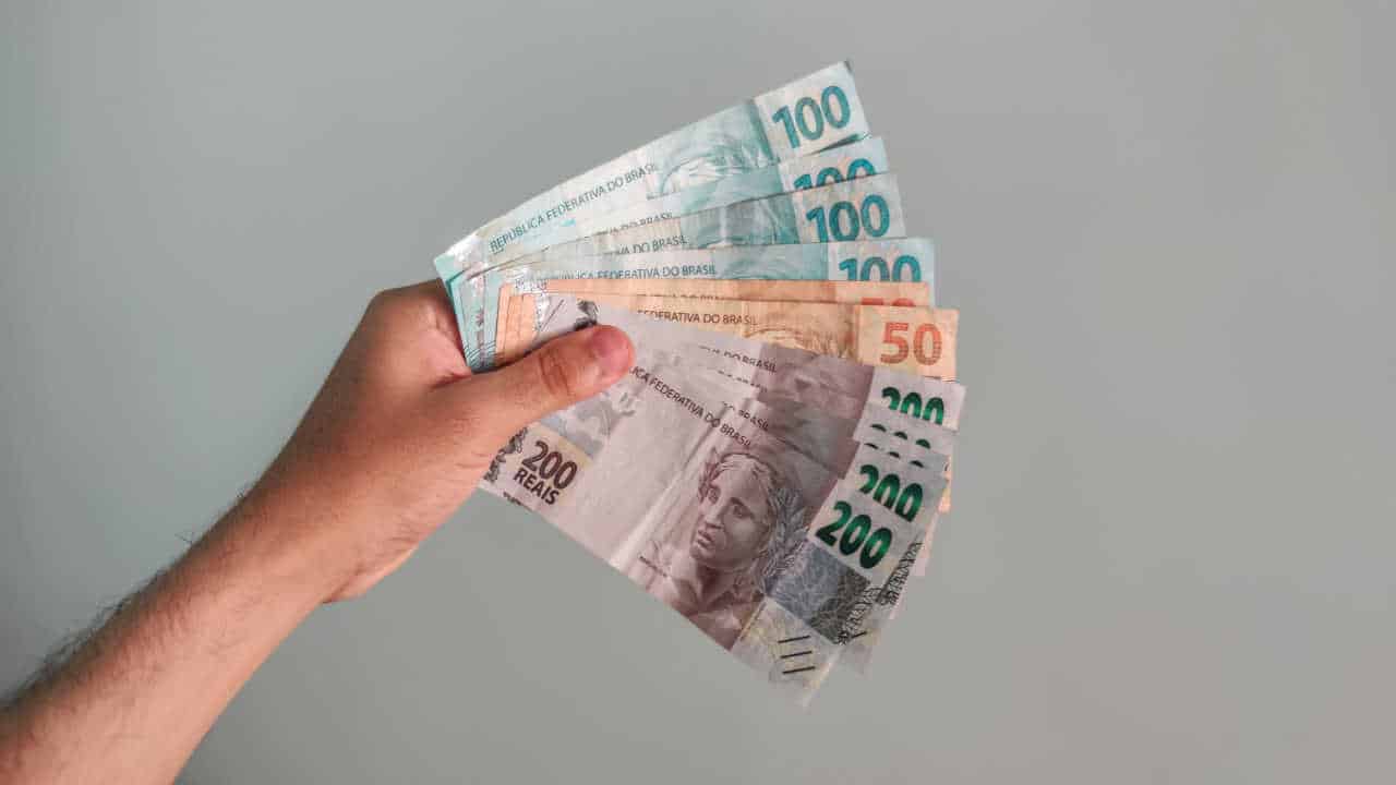 Diversas cédulas de R$ 50 R$ 100 e R$ 200 na mão, em formato de leque