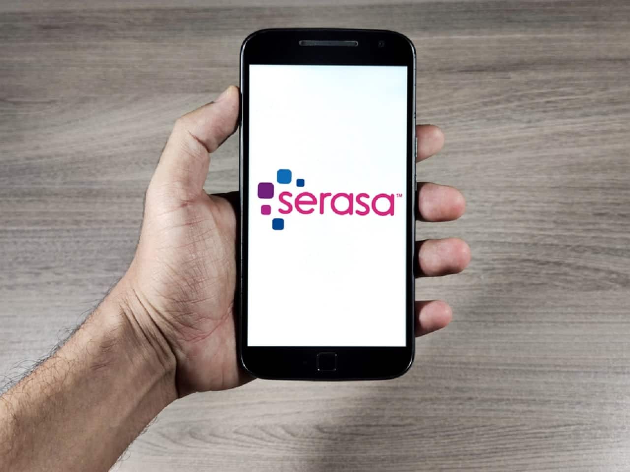Imagem de uma mão segurando um celular com o aplicativo da Serasa aberto