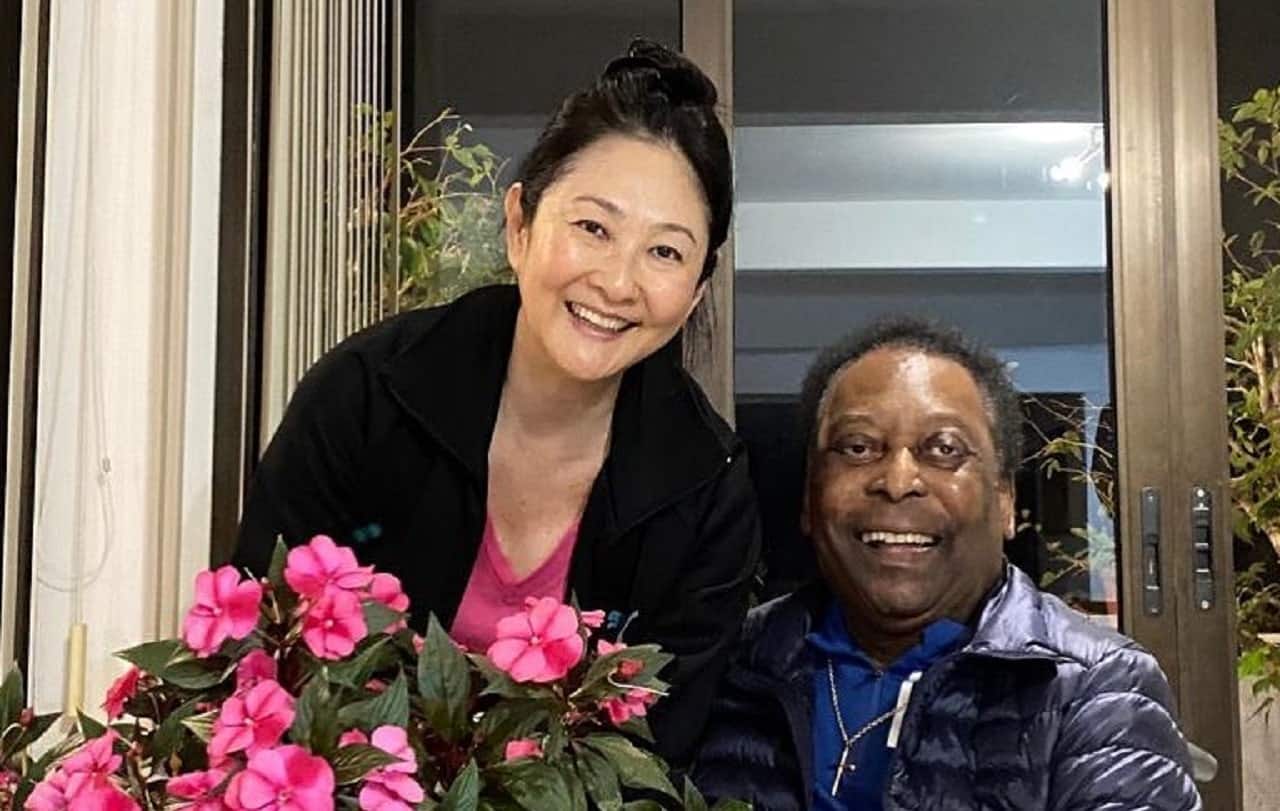 Imagem de Márcia Aoki segurando um buquê de flores junto de seu marido Pelé.