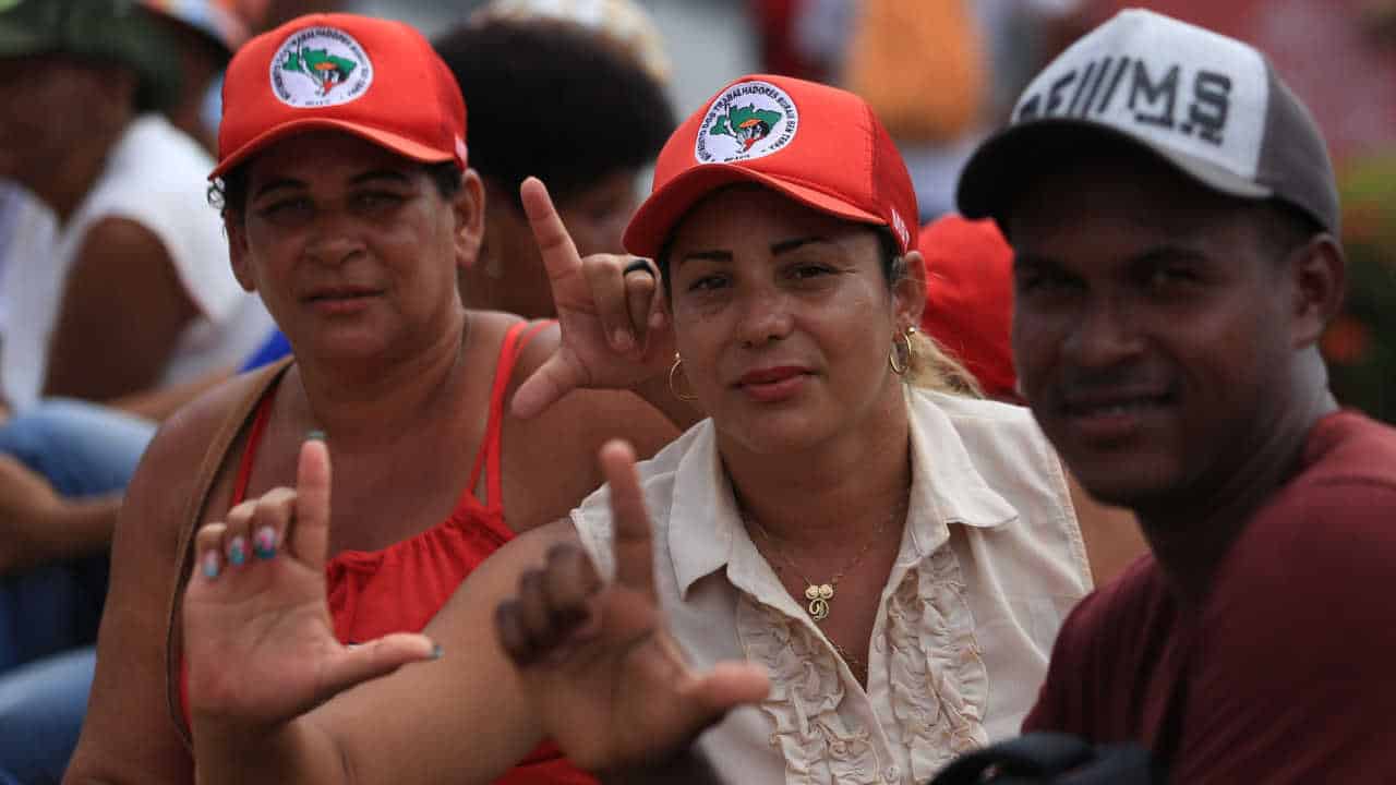 Membros do MST fazem o símbolo do “L” com as mãos.