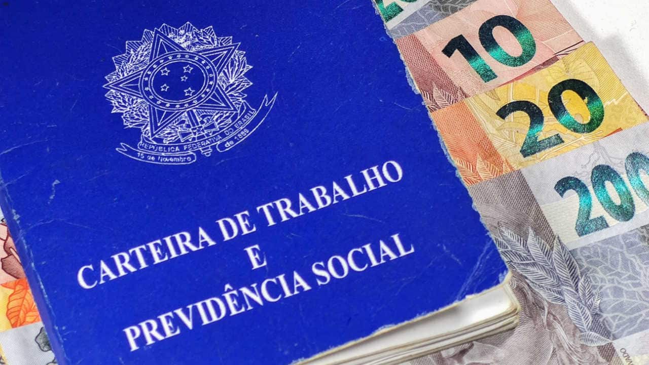 Carteira de trabalho com notas de R$ 10 R$ 20 e R$ 200 por baixo