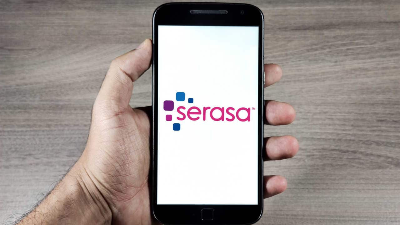 Celular na mão com aplicativo da Serasa aberto na tela inicial
