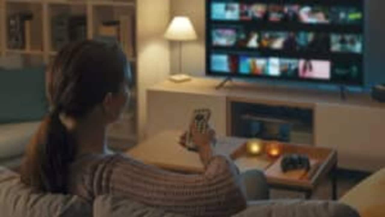 Mulher apontando controle de TV para o aparelho