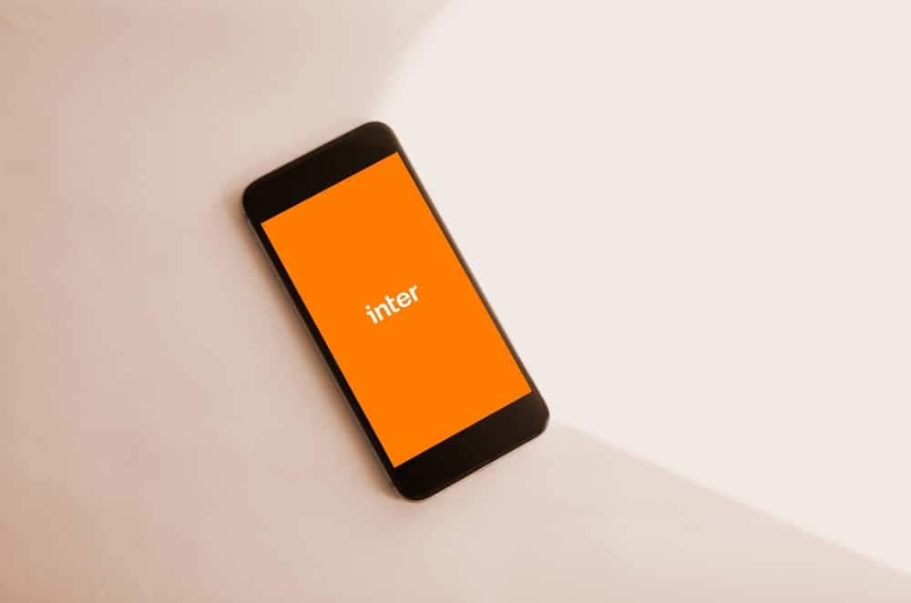 Imagem de um celular com a tela na logo do Banco Inter