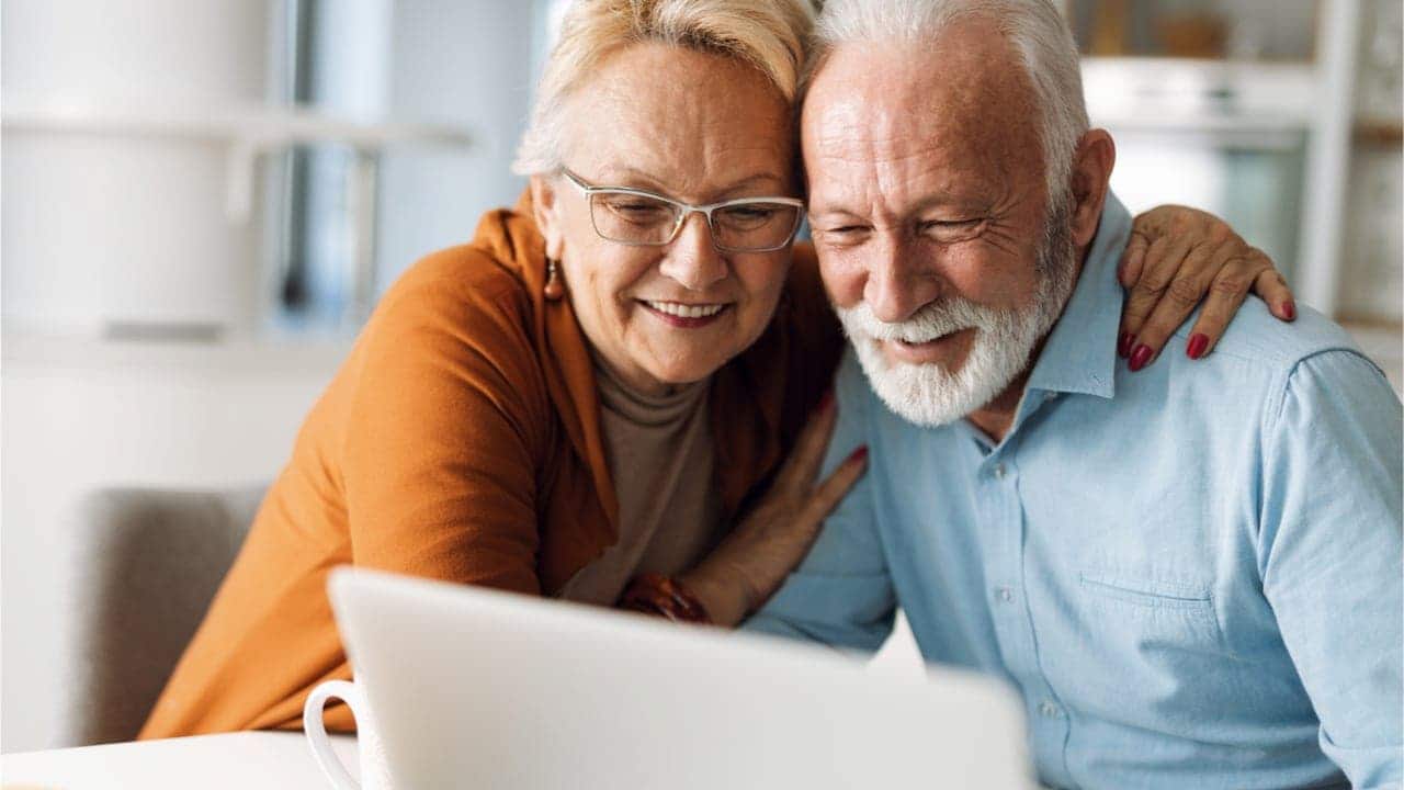 Um casal de idosos olhando para o computador