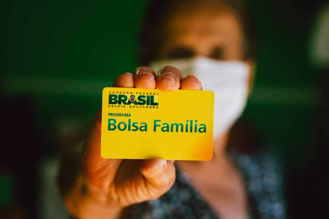 Imagem de uma mulher segurando o cartão do Bolsa Família.