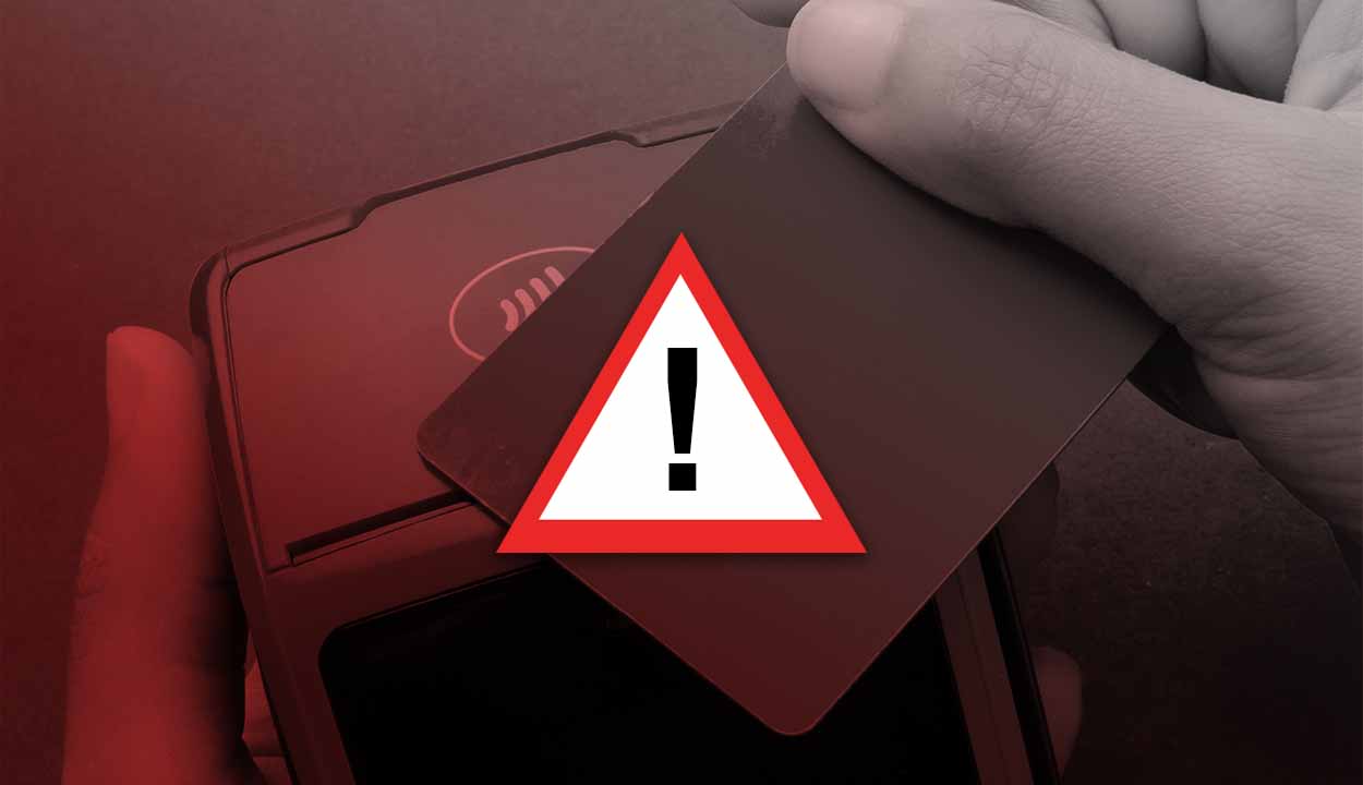 Um cartão diante de uma maquininha com um sinal de alerta em cima