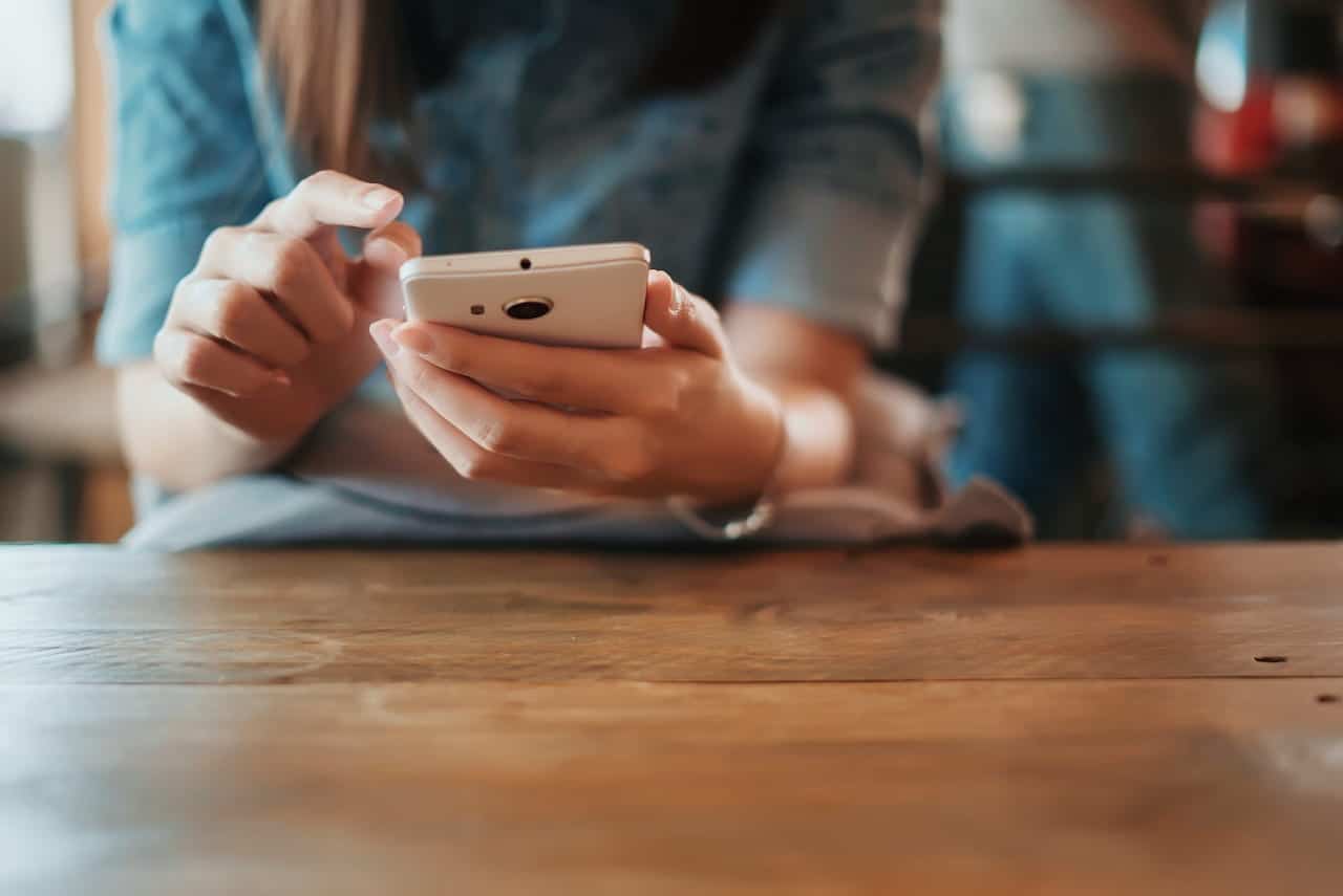 Mão segurando um celular na cor branca. A velocidade de internet será enorme com o 6G.