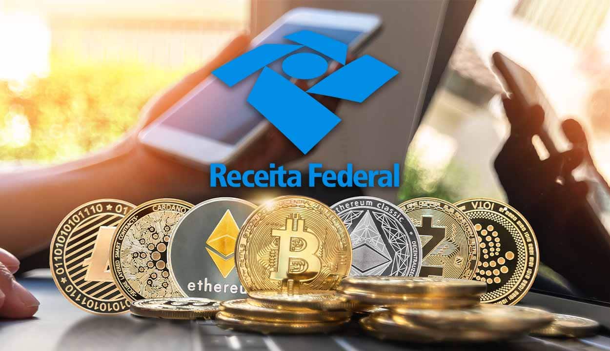 Diferentes criptomoedas sobre uma mesa. Em segundo plano mão segurando celular e logo da Receita federal sobre esse celular.