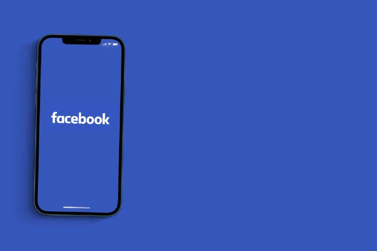 Celular com a tela na logo do Facebook. Fundo azul