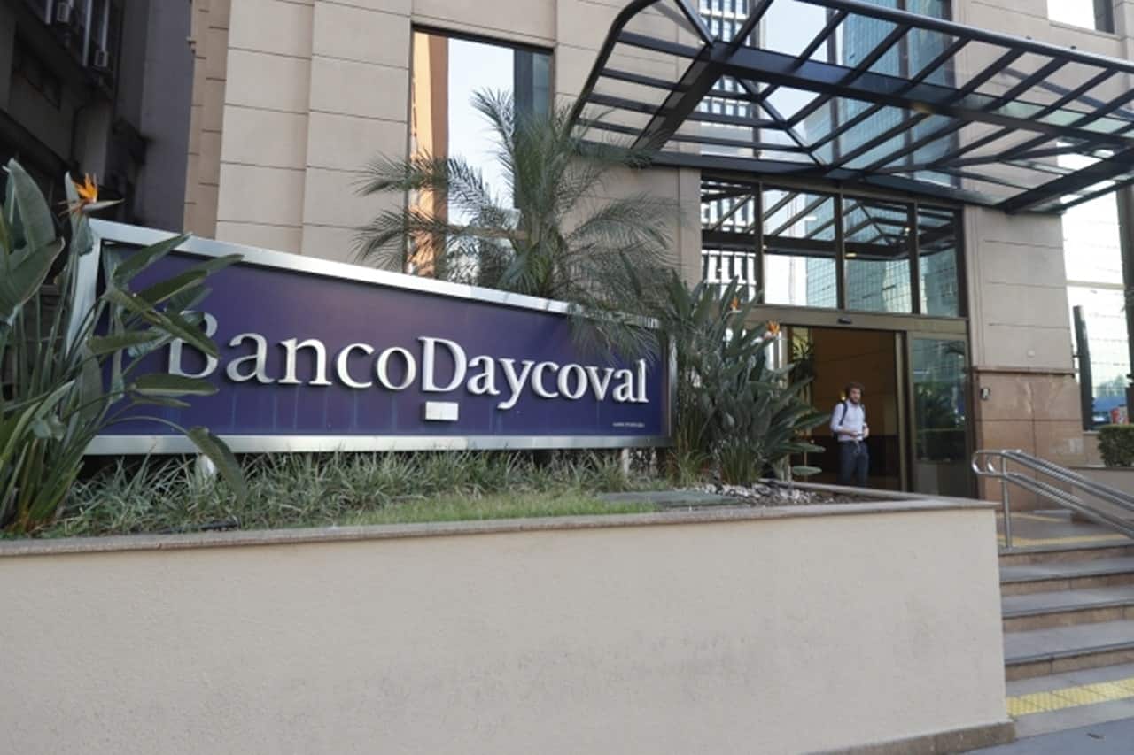 Fachada do Banco Dayvocal, com a identificação do banco em placa azul sobre um jardim de entrada