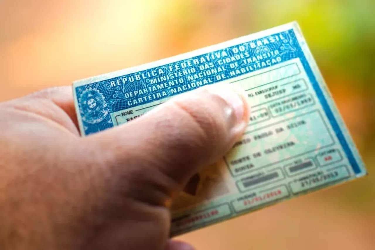 Mão segurando CNH com fundo desfocado