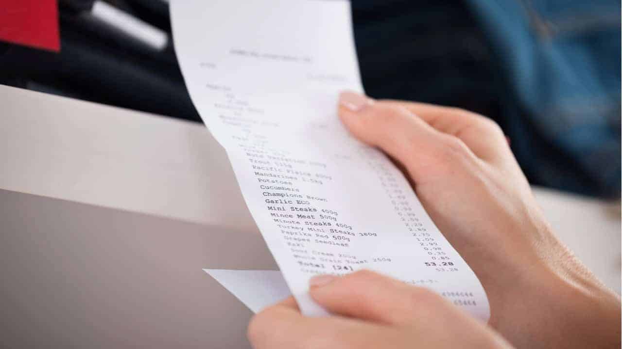 Mão segurando uma nota fiscal em papel branco