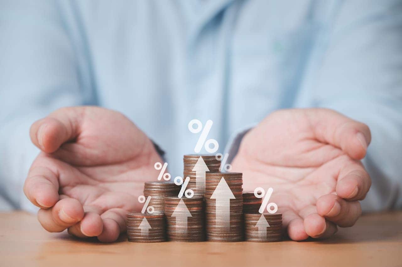Mãos próximas a pilha de moedas indicando crescimento