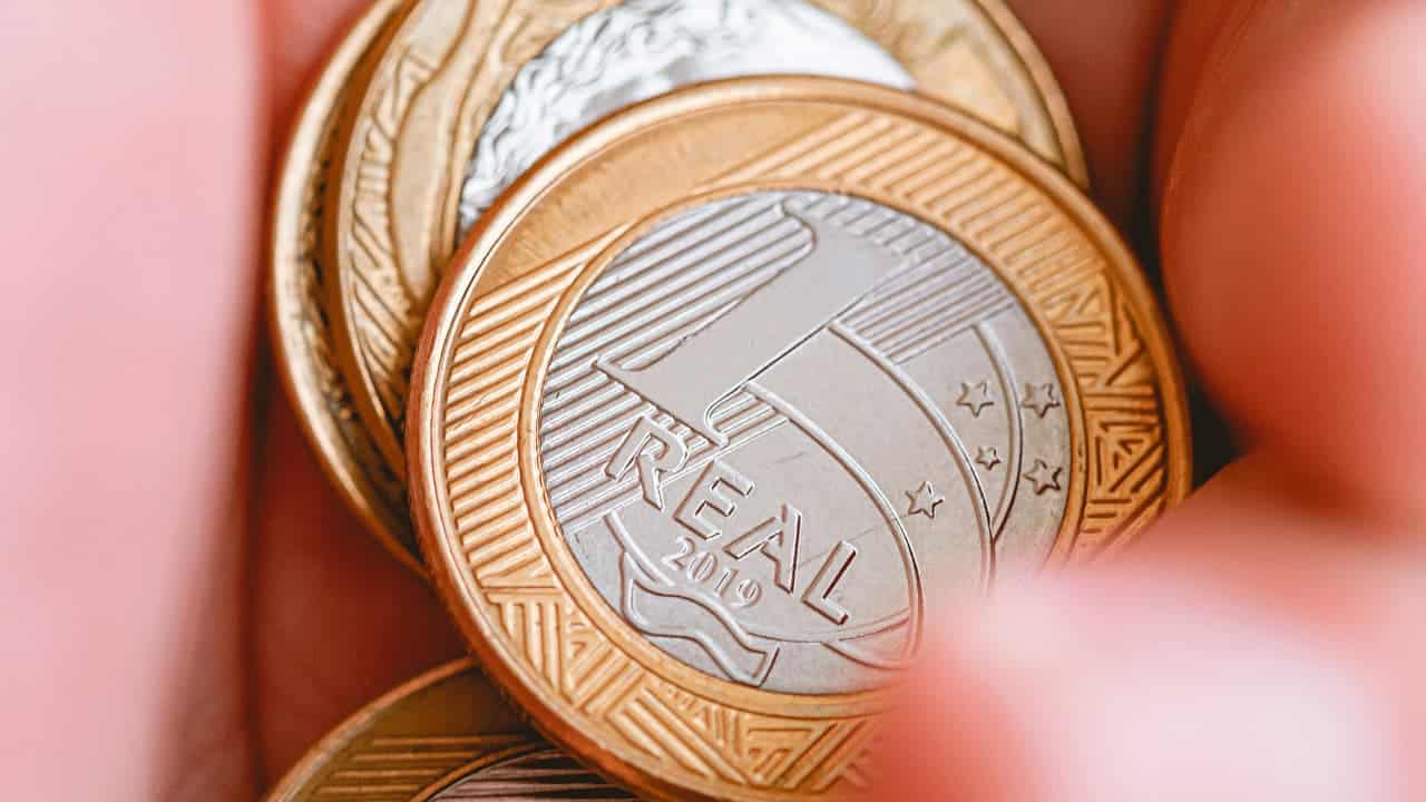 4 moedas de 1 real em uma mão