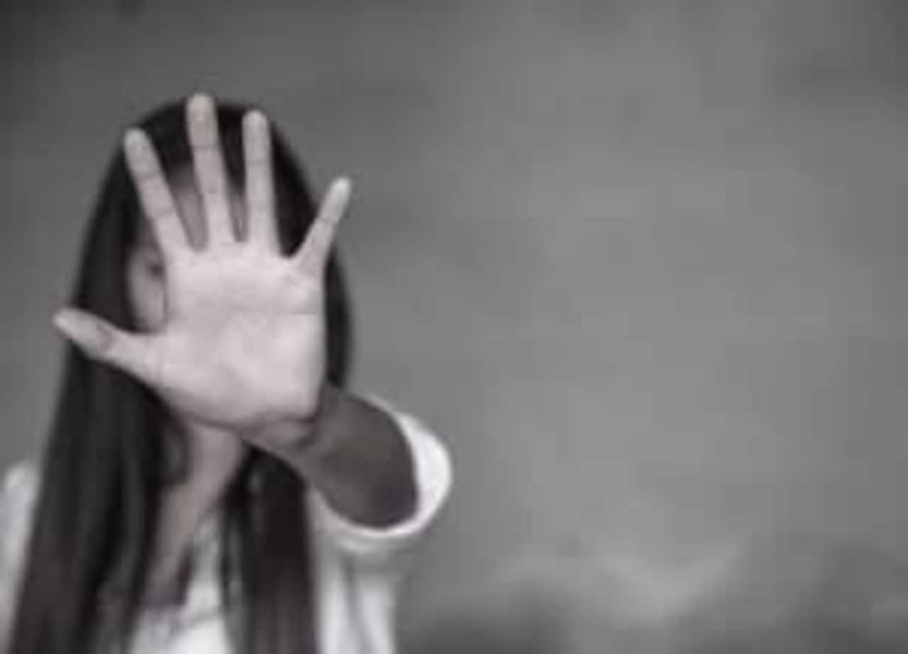 Uma mulher com a mão em frente ao rosto para impedir violência contra as mulheres
