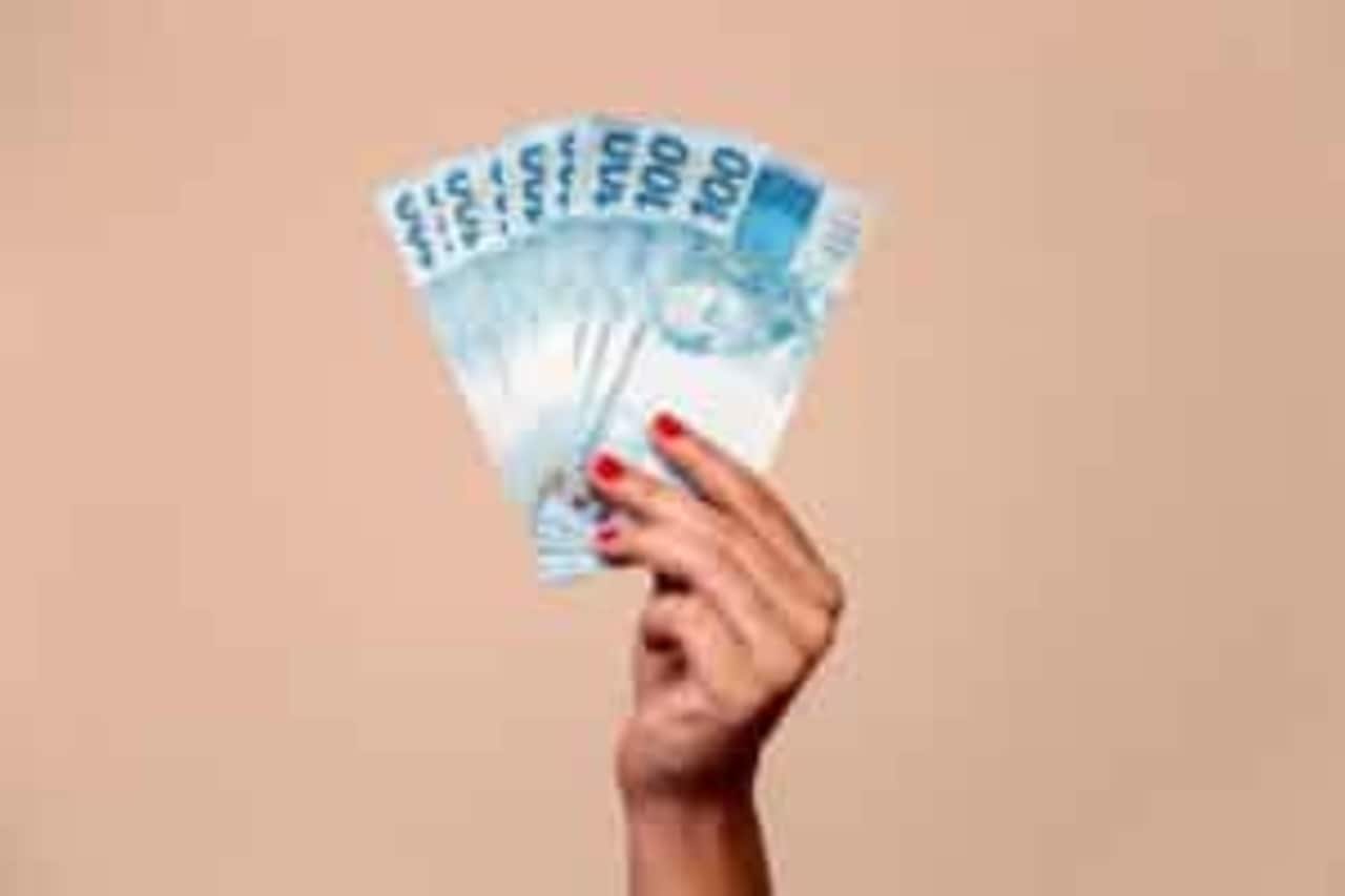 Mão segurando notas de R$100.