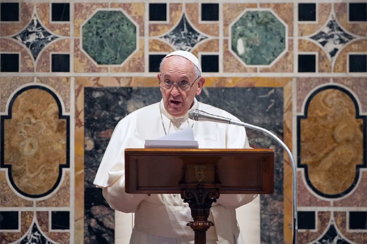 Imagem do Papa Francisco falando em um altar, por meio de um microfone, durante a missa.