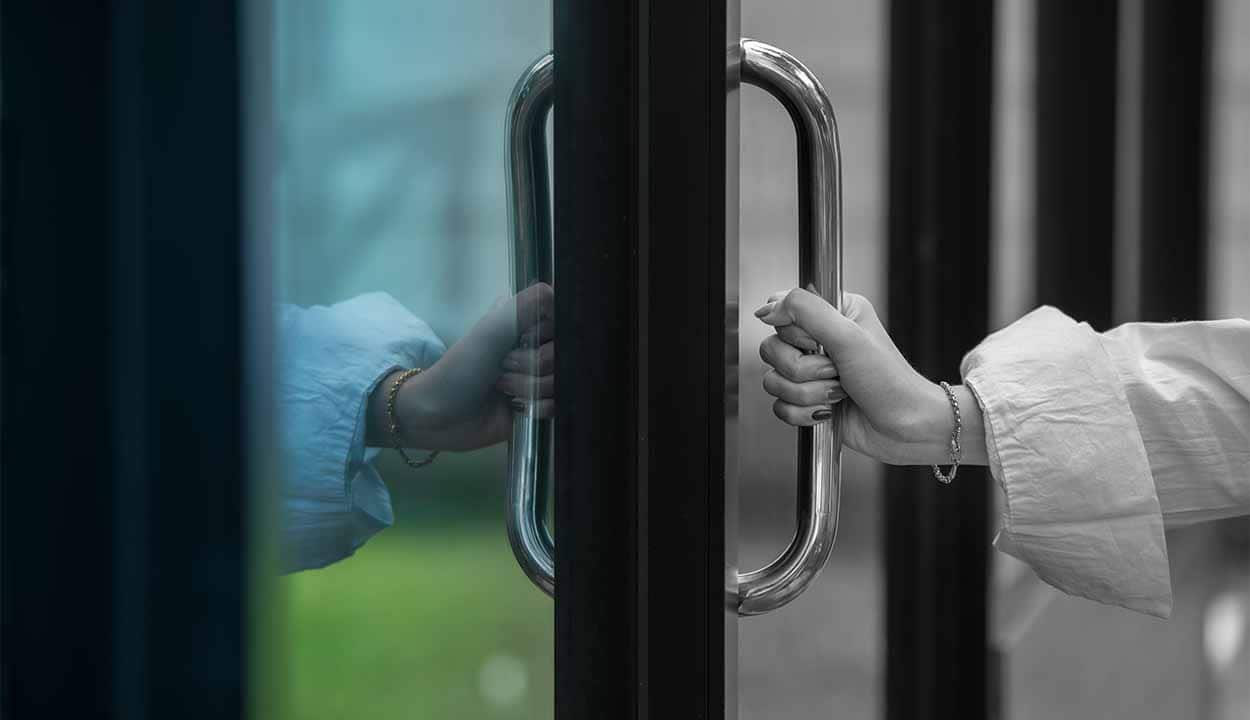 mão segurando puxador de porta para fechar loja física