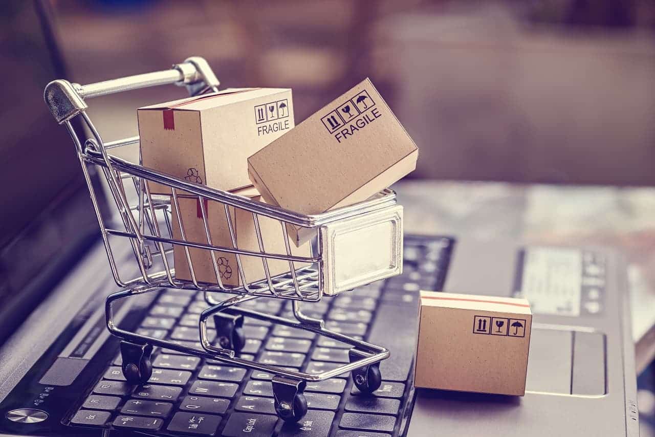 um carro de compras pequeno cheio de caixas de papelão em cima do teclado de um notebook aberto