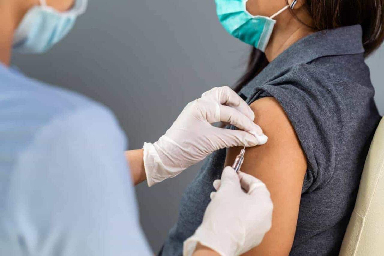 profissional da saúde aplicando vacina em mulher por meio de seringa