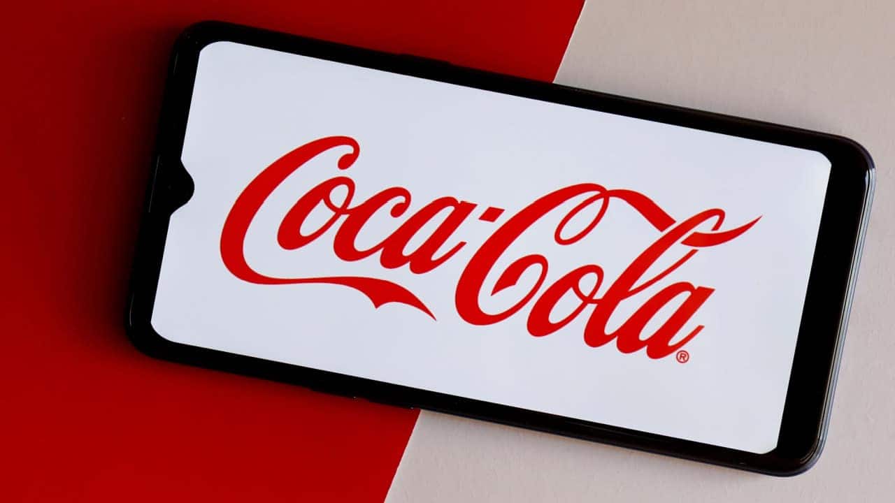 Celular posicionado na horizontal mostrando logo da empresa de bebidas Cola-Cola