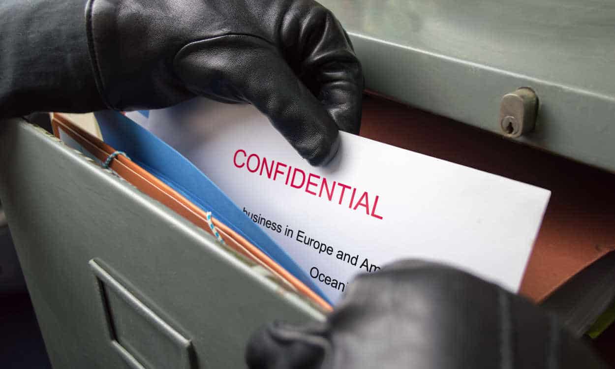 Clouseup em mãos enluvadas pegando um documento confidencial do arquivo