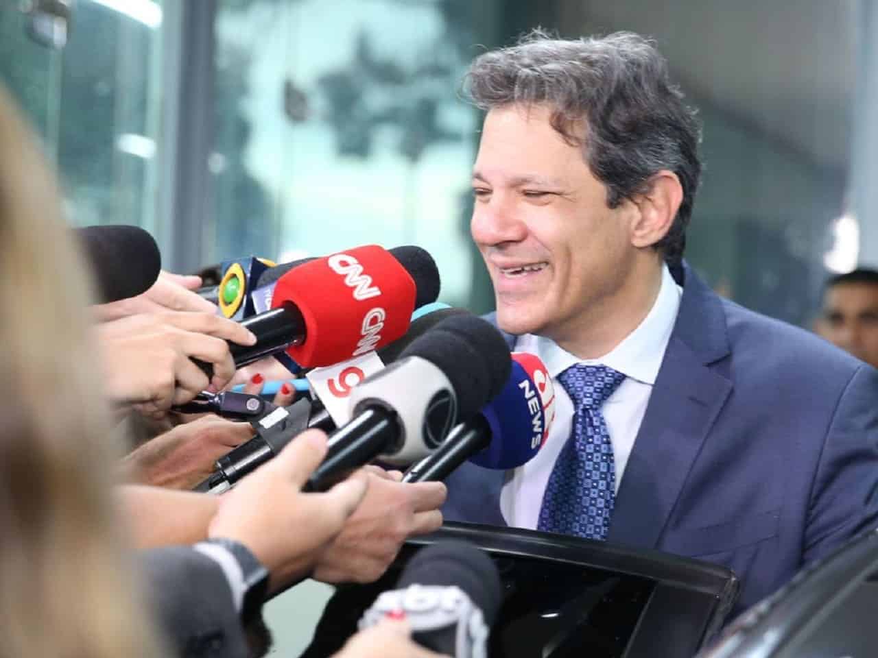 Fernando Haddad, Ministro da Fazenda, dando entrevista para jornalistas, sorrindo.